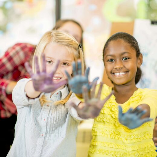 Two girls showing off their finger painted hands.