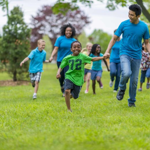 Adults and kids holding hands and racing.